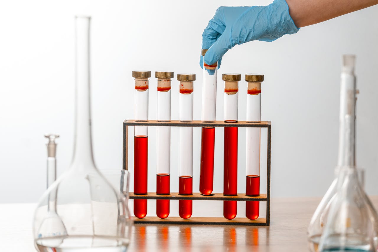 Close-up of gloved hand handling test tubes in a scientific laboratory setting.